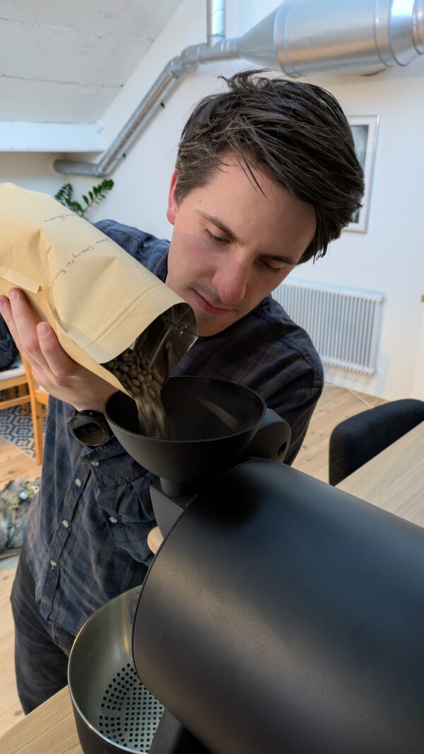 Pouring green beens into the Funnel of the Buller R1 roaster at the start of roasting.