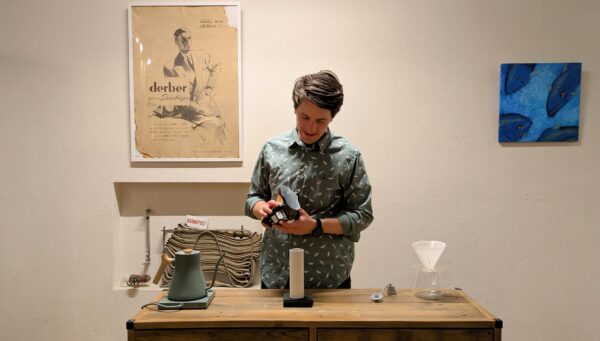 Pouring beans into a Coffee grinder. A Brewing space full of coffee equipment like the Fellow Stagg Pour over kettle and hario v60. The Scale Is a Timemore Blackmirror Nano and the Grinder a Timemore Chestnut c3.