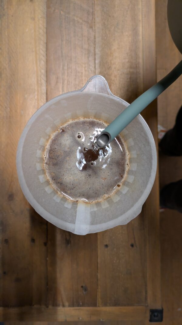 A top view of a coffe brewer (Hario v60), coffee being brewed with hot water from a Fellow Stagg EKG.