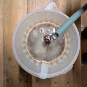A top view of a coffe brewer (Hario v60), coffee being brewed with hot water from a Fellow Stagg EKG.